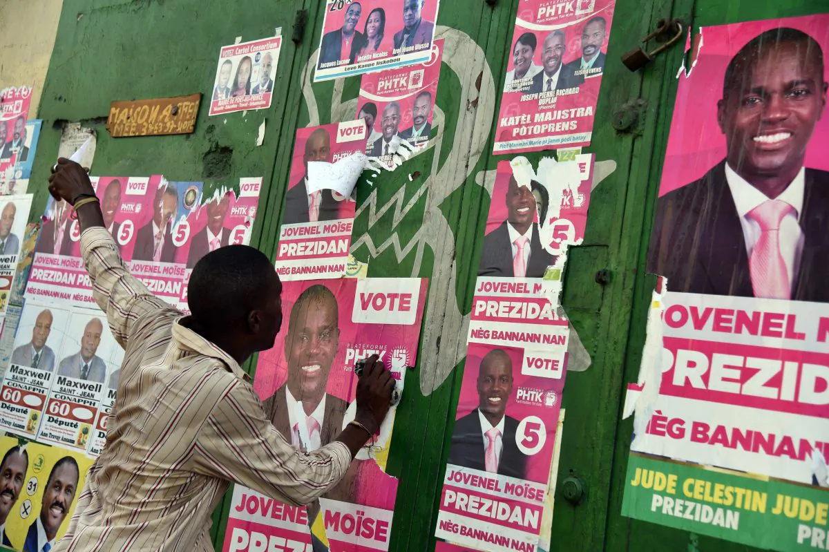 A man tears election posters of the presidential candidate Jovenel Moise during a march of supporters of LAPEH, Fanmi Lavalas and Petit Dessalines political parties in the streets of Port-au-Prince, Haiti, on Nov. 11, 2015. (HECTOR RETAMAL/AFP/Getty Images)