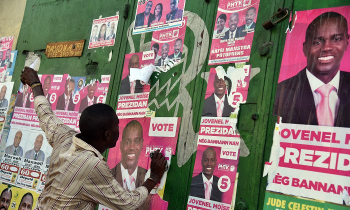 A man tears election posters of the presidential candidate Jovenel Moise during a march of supporters of LAPEH, Fanmi Lavalas and Petit Dessalines political parties in the streets of Port-au-Prince, Haiti, on Nov. 11, 2015. (HECTOR RETAMAL/AFP/Getty Images)