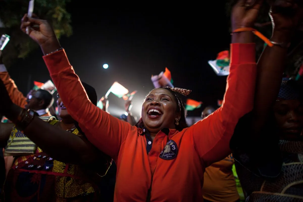 A supporter of presidential election candidate of Burkina Faso Roch Marc Christian Kabore celebrate after preliminary results showed him to be the winner of recent elections, supporters gather outside  Kabore's campaign headquarters  in Ouagadougou, Burkina Faso, Tuesday, Dec. 1, 2015. (AP Photo/Theo Renaut)