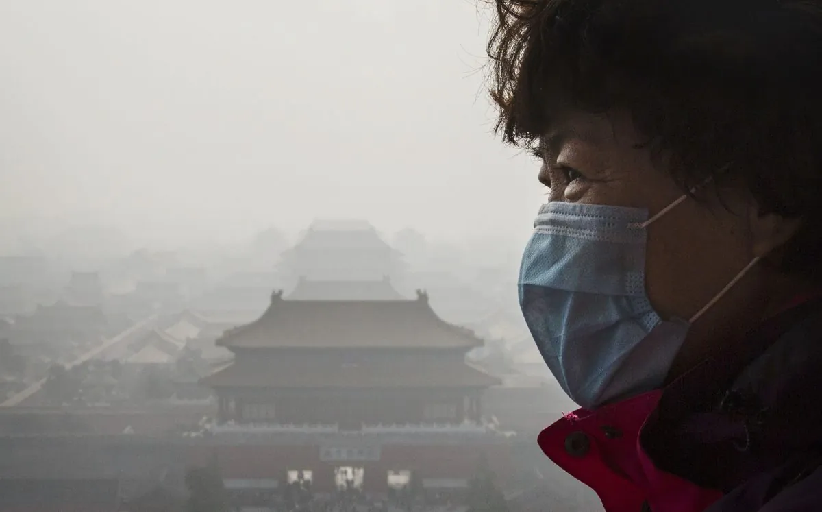 A Chinese woman wears a mask as haze from smog caused by air pollution hangs over the Forbidden City in Beijing, China, on Nov. 15, 2015.  (WHO). (Kevin Frayer/Getty Images)