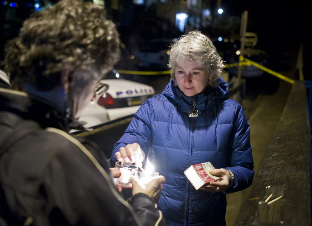 D.J. Thomson (R) and Joyce Levine light candles on Kennedy Street after hearing about the death of Mayor Stephen "Greg" Fisk in Juneau, Alaska, on Nov. 30, 2015. (Michael Penn/The Juneau Empire via AP)