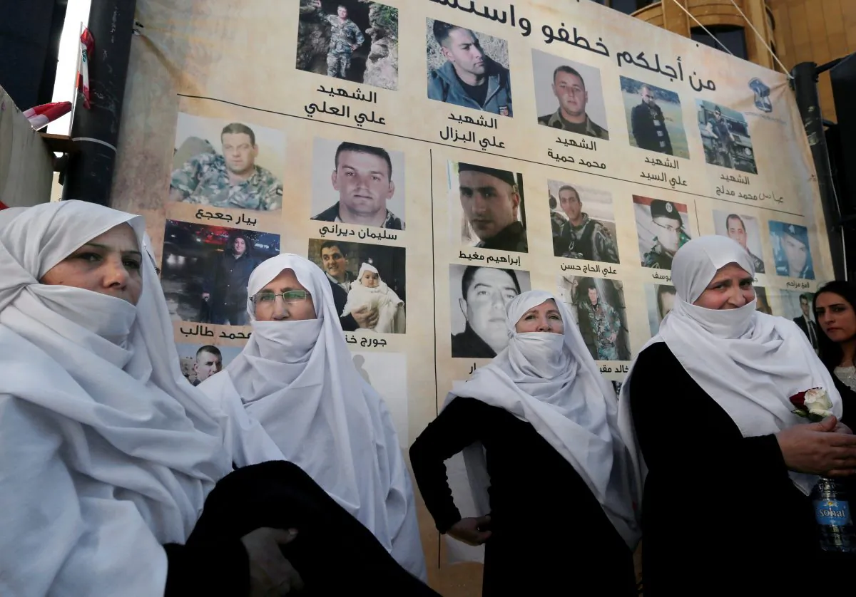 Lebanese Druze women stand next to posters with pictures of soldiers and policemen who were kidnapped by militants from the Islamic State and al-Qaida's branch in Syria, the Nusra Front, during a protest in downtown Beirut, Lebanon, Tuesday, Dec. 1, 2015. Syria's al-Qaida branch was releasing on Tuesday a group of Lebanese soldiers and policemen held captive since August 2014 as part of a swap deal brokered by Qatar that included Lebanon setting free an unspecified number of prisoners wanted by the militant group. (AP Photo/Bilal Hussein)