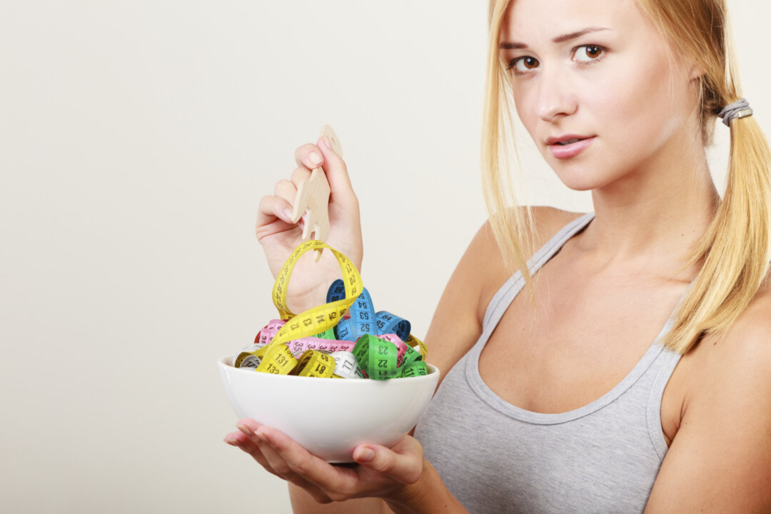 Diet, healthy eating, weight loss and slim body concept. Fit fitness girl holding bowl with many colorful measuring tapes