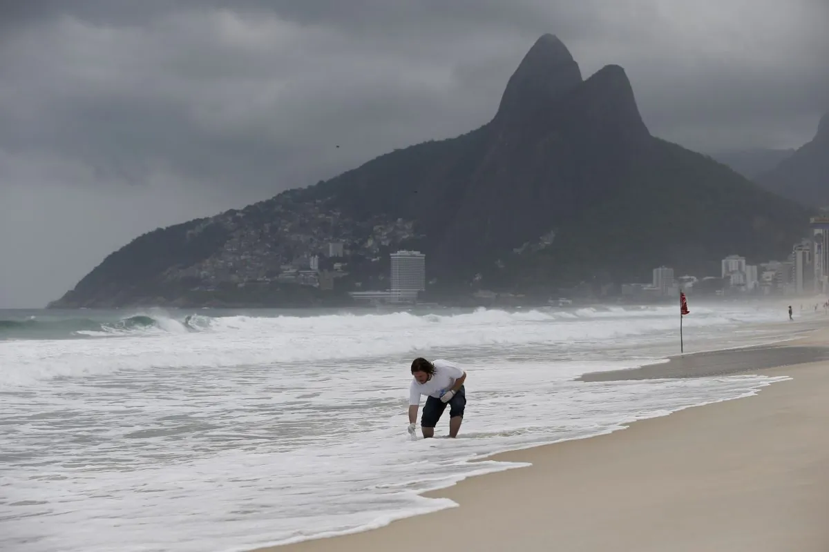 Doctoral candidate Rodrigo Staggemeier collects water along the shore of Ipanema Beach in Rio de Janeiro, Brazil, on Oct. 26, 2015. Many of the estimated 350,000 foreigners to visit during the 2016 Olympics are expected to take a dip at the popular beach. (AP Photo/Silvia Izquierdo)
