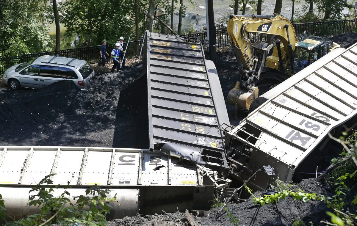 Officials (top L) inspect part of a CSX freight train that derailed alongside a parking lot overnight in Ellicott City, Md., on Aug. 21, 2012. A little-known truth about North American railroads: No rules govern when rail becomes too worn down. Since 2000, U.S. officials blamed rail wear as the direct cause of 111 derailments causing $11 million in damage. (AP Photo/Patrick Semansky)