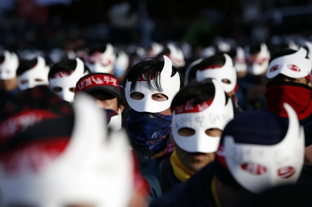 South Korean protesters attend an anti-government rally in downtown Seoul, South Korea, Saturday, Dec. 5, 2015. Wearing white half-masks and carrying flowers and banners, thousands of South Koreans marched in Seoul on Saturday against conservative President Park Geun-hye, who had compared masked protesters to terrorists after clashes with police broke out at a rally last month. (AP Photo/Lee Jin-man)