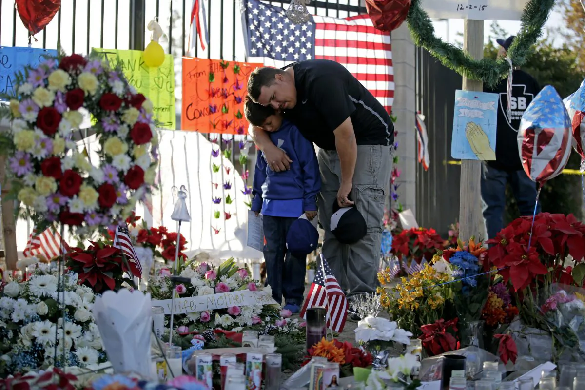Gary  Mendoza, and his son Michael pay their respects at a makeshift memorial site honoring Wednesday's shooting victims in San Bernardino, Calif., on Dec. 7, 2015. (AP Photo/Jae C. Hong)