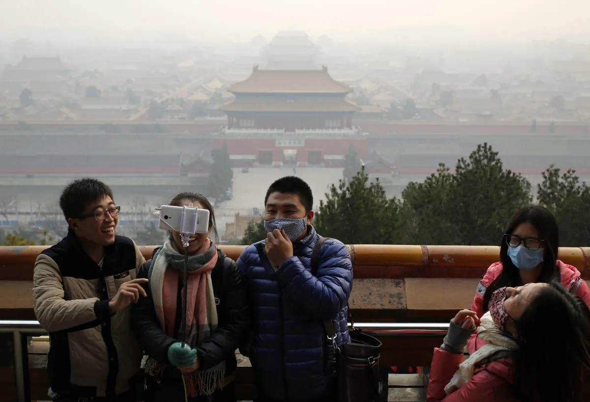 Visitors, some wearing masks to protect themselves from pollutants, share a light moment as they take a selfie at the Jingshan Park on a polluted day in Beijing on Dec. 7, 2015. (AP Photo/Andy Wong)