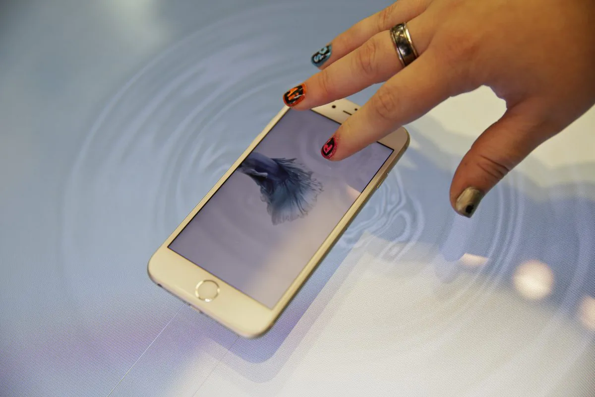 A woman presses an Apple iPhone 6s on a 3D touch table at the Apple store on  Nov. 13. (AP Photo/Eric Risberg)