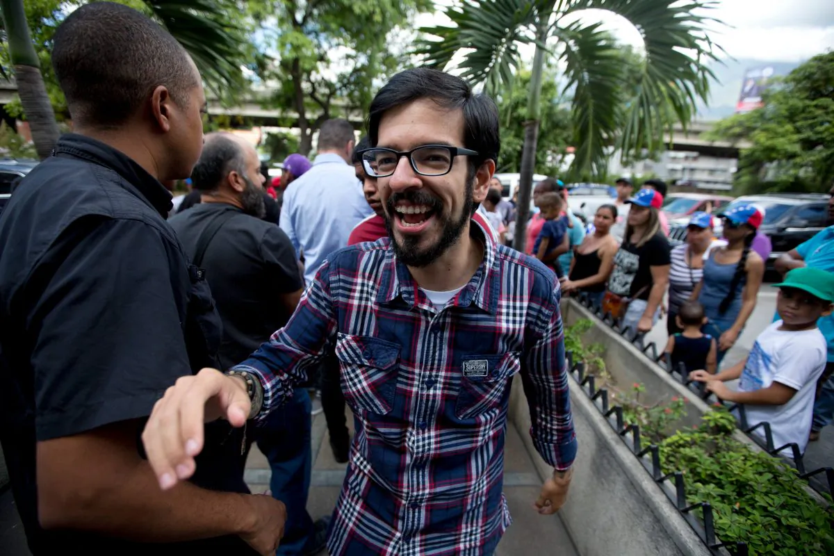 Opposition lawmaker Miguel Pizarro, who was reelected to Congress, greets supporters as he arrives for a news conference in Caracas, Venezuela, Monday, Dec. 7, 2015. Venezuela's opposition won control of the National Assembly by a landslide in Sunday's election, stunning the ruling party and altering the balance of power 17 years after the late Hugo Chavez was elected president. (AP Photo/Fernando Llano)
