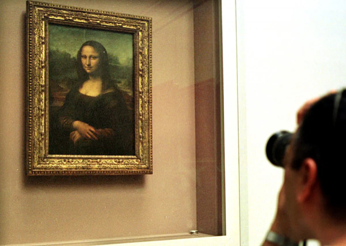 A man takes a photograph of The Mona Lisa painting, behind a protective glass, in the Louvre museum in Paris in a Monday April 26, 2004 file photo. (AP Photo/Amel Pain, File)