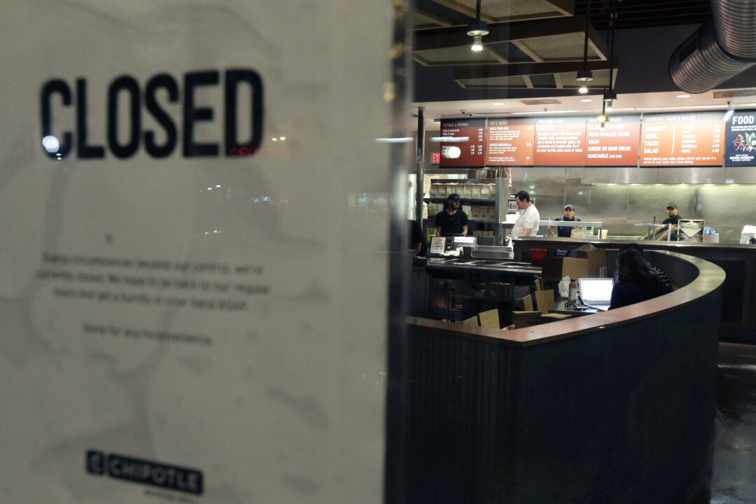 People stand inside a closed Chipotle restaurant on Monday, Dec. 7, 2015, in the Cleveland Circle neighborhood of Boston. Chipotle said late Monday that it closed the restaurant after several students at Boston College, including members of the men’s basketball team, reported “gastrointestinal symptoms” after eating at the chain. The school said it was working with local health officials to determine the cause of the illness. (AP Photo/Steven Senne)