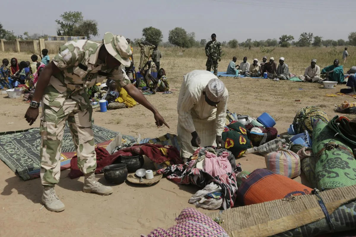 Soldiers screen newly arrived displaced people at Furore camp in Yola, Nigeria, on Tuesday, Dec. 8, 2015, who claim were chased out of their villages by Cameroon troops. Cameroonian troops crossed the border into Nigeria, killing and pillaging and ordering people to abandon their villages, according to hundreds of survivors arriving at a refugee transit center after walking for days. (AP Photo/Sunday Alamba)