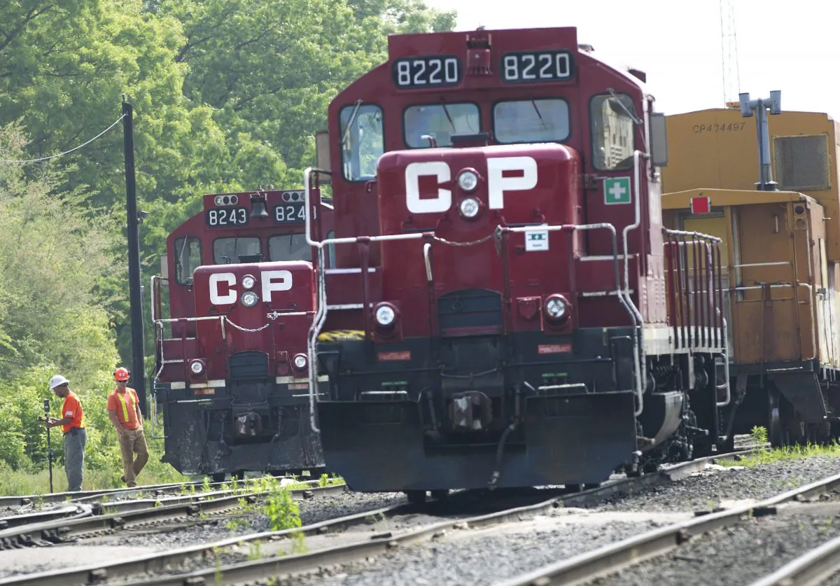 Surveyors work next to Canadian Pacific trains in Toronto on May 23, 2012. Canadian Pacific has revised its takeover bid for Norfolk Southern, saying that it should ease fears that the railroad deal would be shot down by regulators. Norfolk Southern Corp. rejected the initial bid, saying it was grossly inadequate and risky. It said Tuesday, Dec. 8, 2015, that the new offer was more uncertain and risky, in part because there was less cash consideration. (Nathan Denette/The Canadian Press via AP)