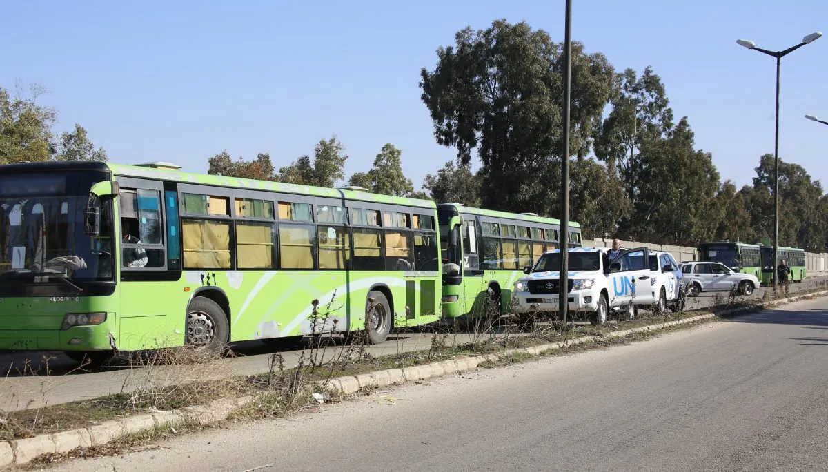 Buses carrying gunmen leave the Waer neighborhood, in the central city of Homs, Syria, Wednesday, Dec. 9, 2015. (AP Photo)