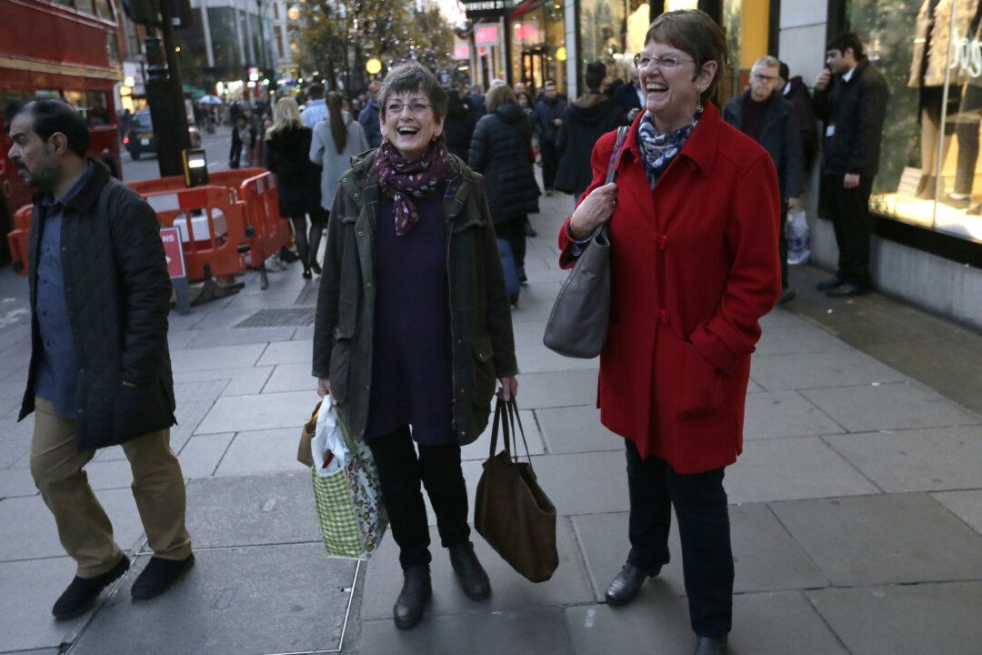 Hazel Newton, centre left, poses for a picture with her sister as they walk down Oxford Street, in London, Wednesday, Dec. 9, 2015. (AP Photo/Tim Ireland)
