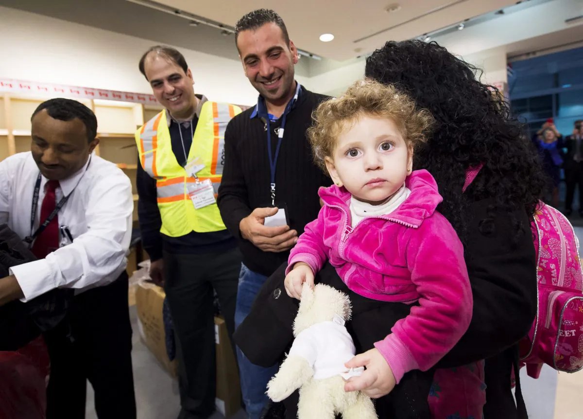 Madeleine Jamkossian, right, arrives with her family, refugees fleeing from Syria, at Pearson International airport, in Toronto, on Dec. 11, 2015. (Nathan Denette/The Canadian Press via AP)