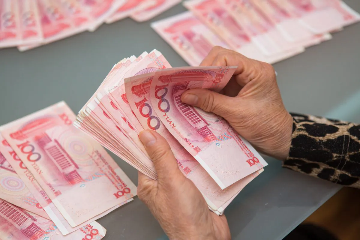 A woman counts Chinese yuan bills worth thousands of dollars in Vancouver, Canada, on Oct. 27, 2015. (Benjamin Chasteen/Epoch Times)