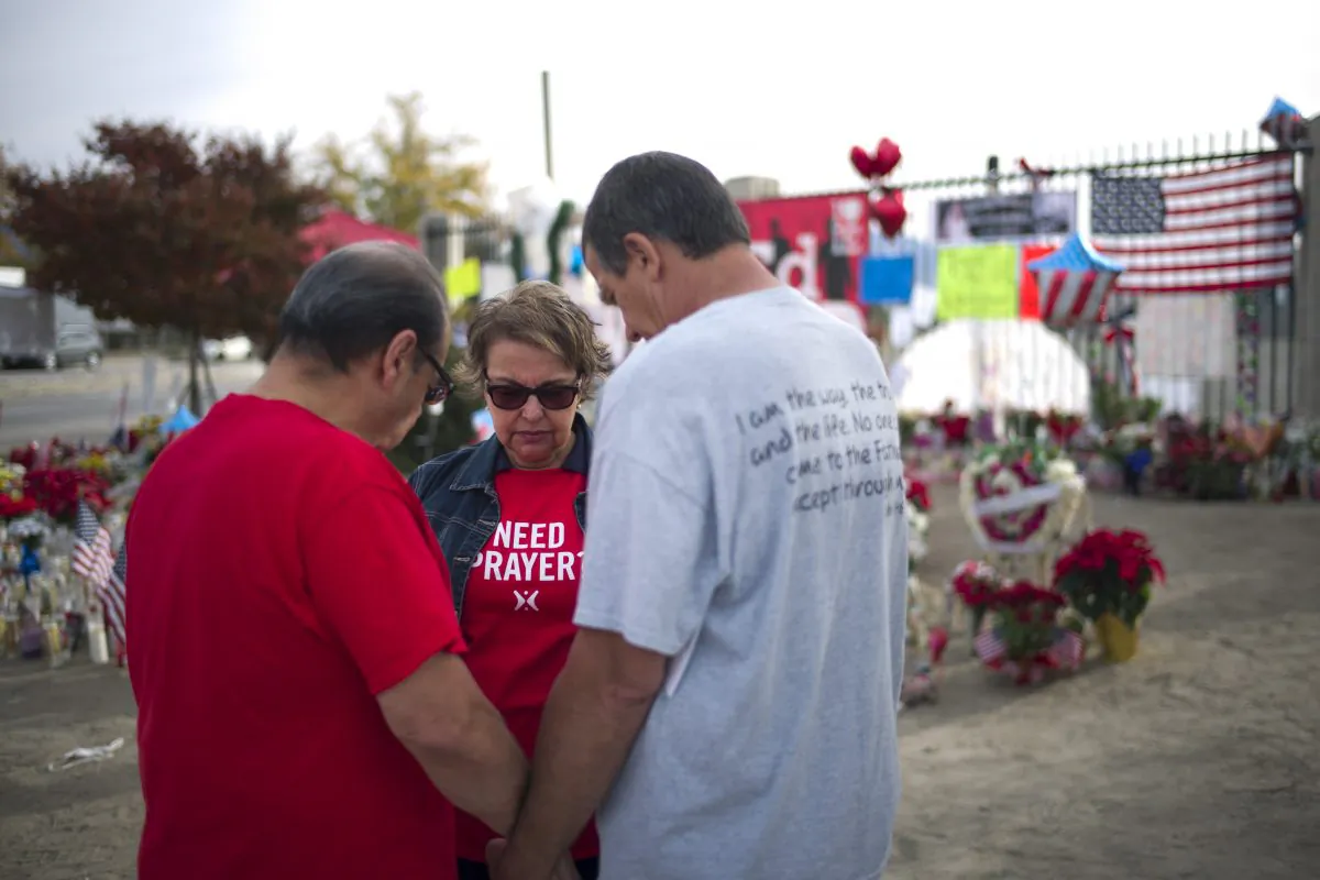 Ray Molina, from left, Molina's wife, Yvonne, and Leonard Lynch pray at a makeshift memorial set up near the Inland Regional Center, the site of last week's fatal shooting that killed 14 people, Wednesday, Dec. 9, 2015, in San Bernardino, Calif. The two San Bernardino shooters were radicalized at least two years ago, a year before one of them came to the U.S. on a fiancée visa, and discussed jihad and martyrdom as early as 2013, FBI Director James Comey said Wednesday. (AP Photo/Jae C. Hong)