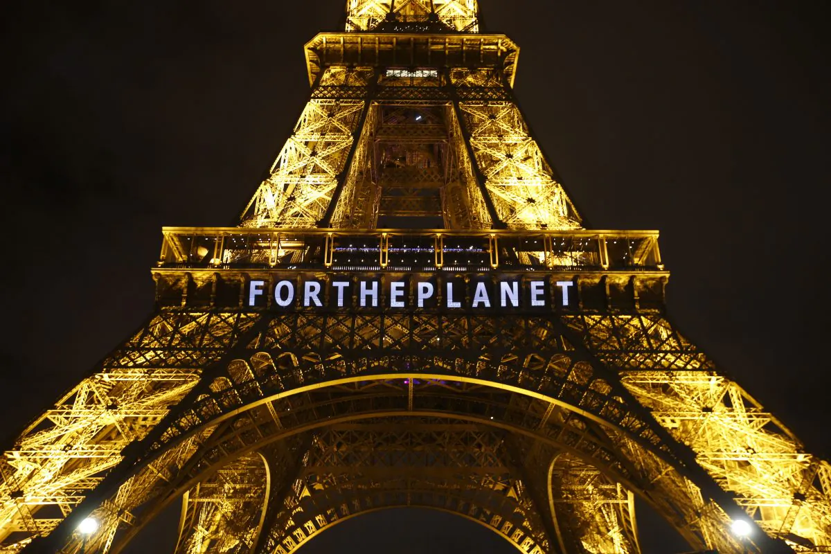 The slogan "FOR THE PLANET" is projected on the Eiffel Tower as part of the COP21, U.N. Climate Change Conference in Paris, France, on Friday, Dec. 11, 2015. (AP Photo/Francois Mori)