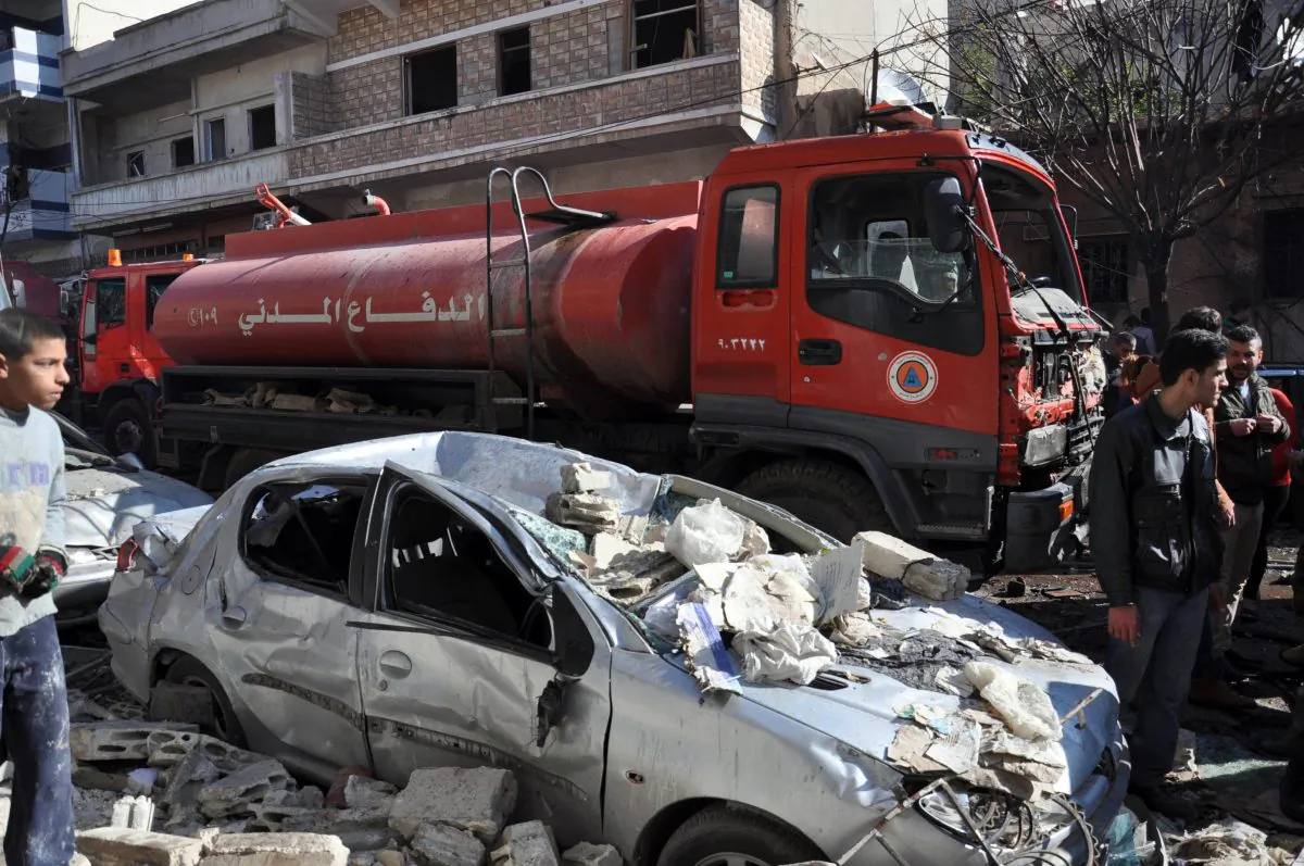 A firefighter truck is seen next to a destroyed car at the site of a car bomb explosion where 16 civilians were killed and a hundred wounded in al-Zahra neighborhood in Homs, Syria, on Dec. 12, 2015. (STR/AFP/Getty Images)