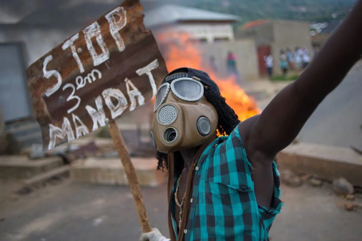 A Burundian protester wearing a gas mask holds a sign that reads 'Stop the third mandate' near a burning barricade in the Mugasa neighbourhood of Bujumbura on May 6, 2015. (Phil Moore/AFP/Getty Images)