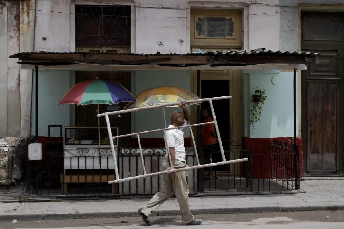 Ruben Font carries a scaffold piece to his home in Havana, Cuba, on May 23, 2011. Cuba has reached a landmark agreement with foreign creditors over billions of dollars in unpaid debt dating back 25 years. (AP Photo/Franklin Reyes)