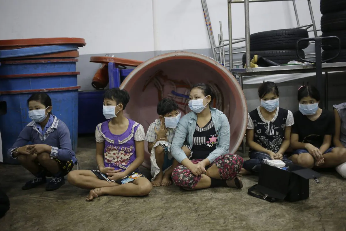 In this Monday, Nov. 9, 2015 photo, children and teenagers sit together to be registered by officials during a raid on a shrimp shed in Samut Sakhon, Thailand. (AP Photo/Dita Alangkara)
