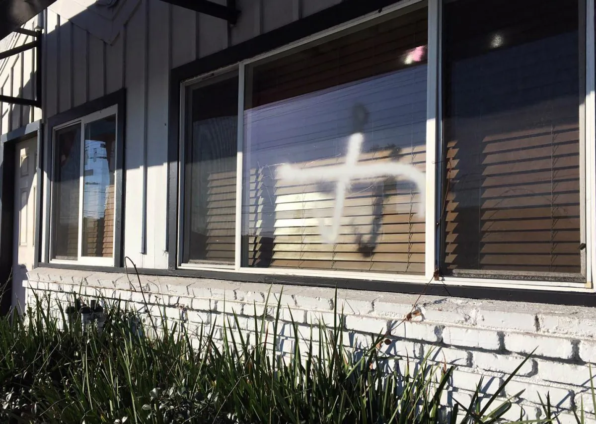This photo provided by the Ahmadiyya Muslim Community muslimsforpeace.org shows crosses in spray paint vandalizing windows at the Ahmadiyya Muslim Community Baitus-Salaam Mosque in Hawthorne, Calif., Sunday, Dec. 13, 2015. (Ahmadiyya Muslim Community muslimsforpeace.org via AP)