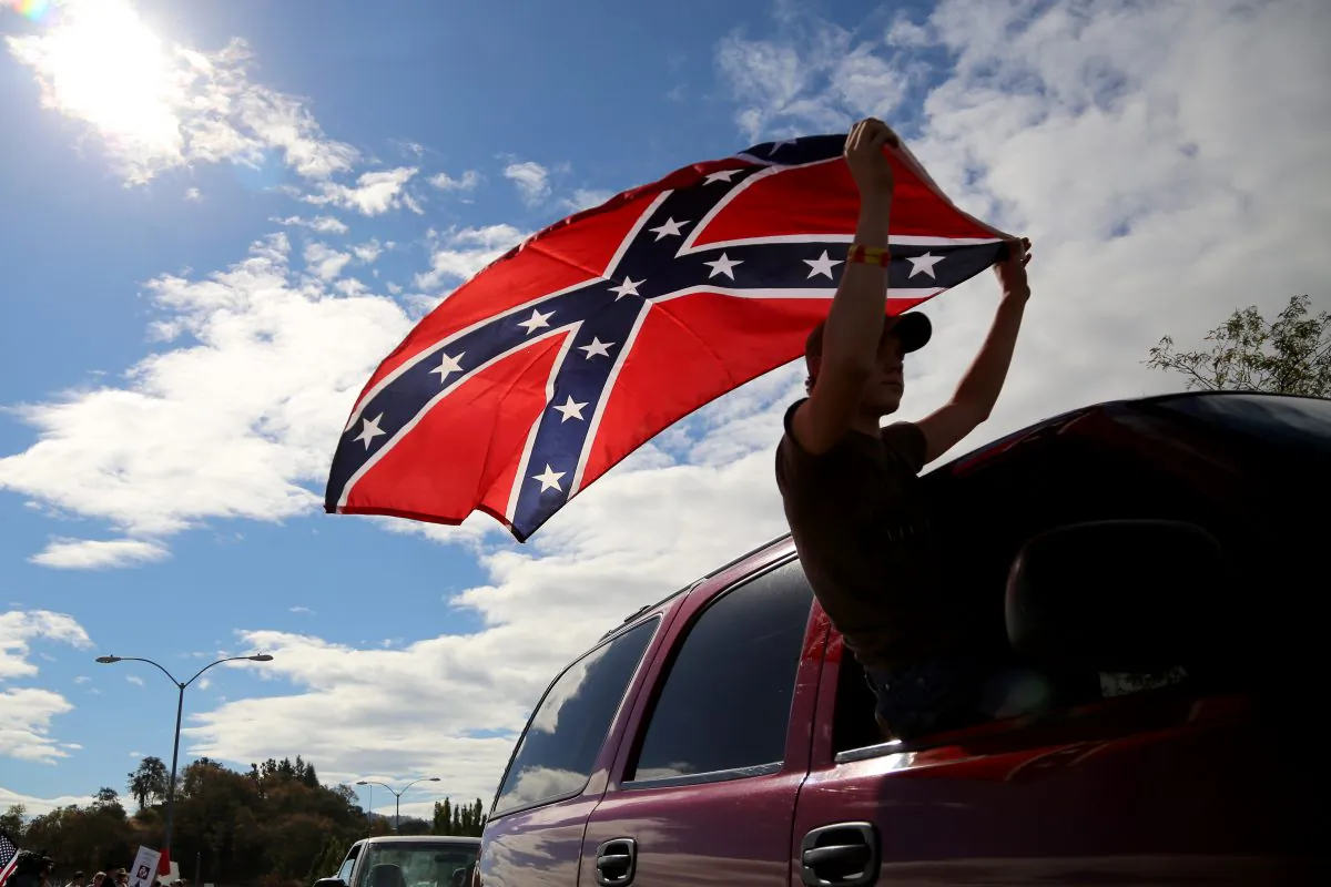 A man waves a Confederate battle flag as he drives away from Roseburg Regional Airport in Roseburg, Ore. in a file photograph. (AP Photo/Ryan Kang)