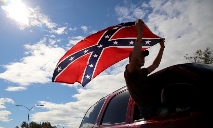 A man waves a Confederate battle flag as he drives away from Roseburg Regional Airport in Roseburg, Ore. in a file photograph. (AP Photo/Ryan Kang)