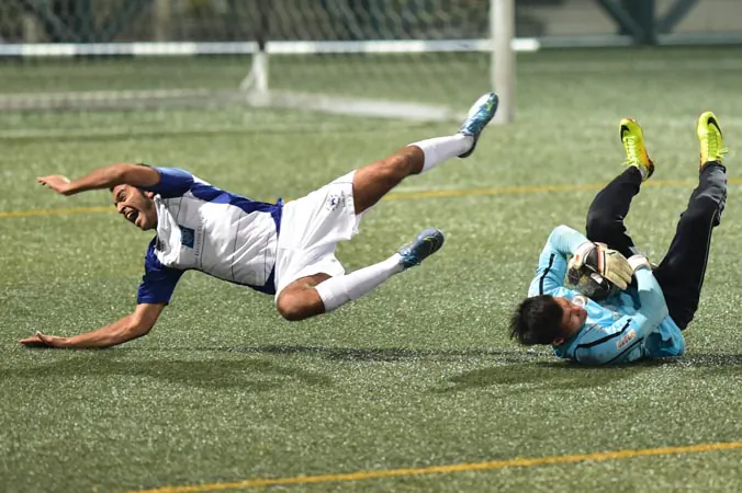 Lucky Mile player Shaun Melwani takes a tumble as Citizen goalkeeper saves the ball during Citizen's 4-1 win in HKFA first division game at Hong Kong Football Club on Sunday Dec 13, 2015. (Bill Cox/Epoch Times)