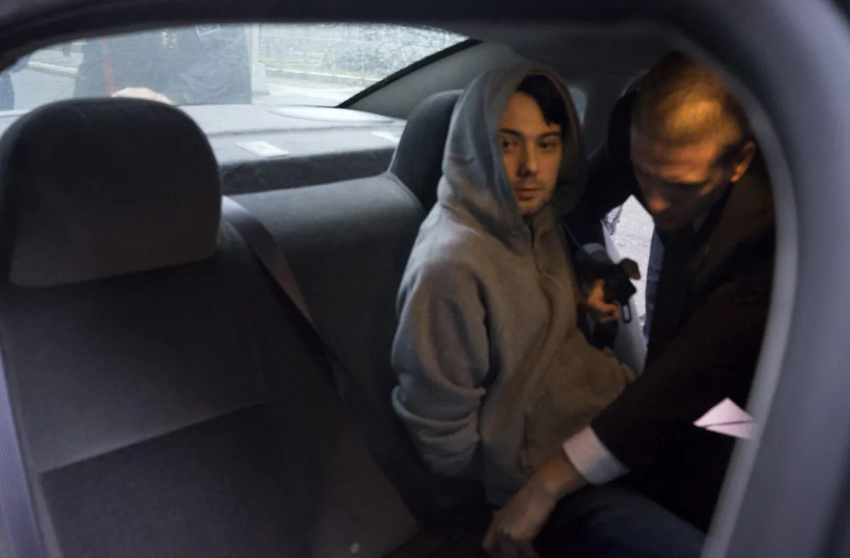 Martin Shkreli, the former hedge fund manager under fire for buying a pharmaceutical company and ratcheting up the price of a life-saving drug, is belted into an awaiting car after being taken into custody following a securities probe, in New York, on Dec. 17, 2015. (AP Photo/Craig Ruttle)