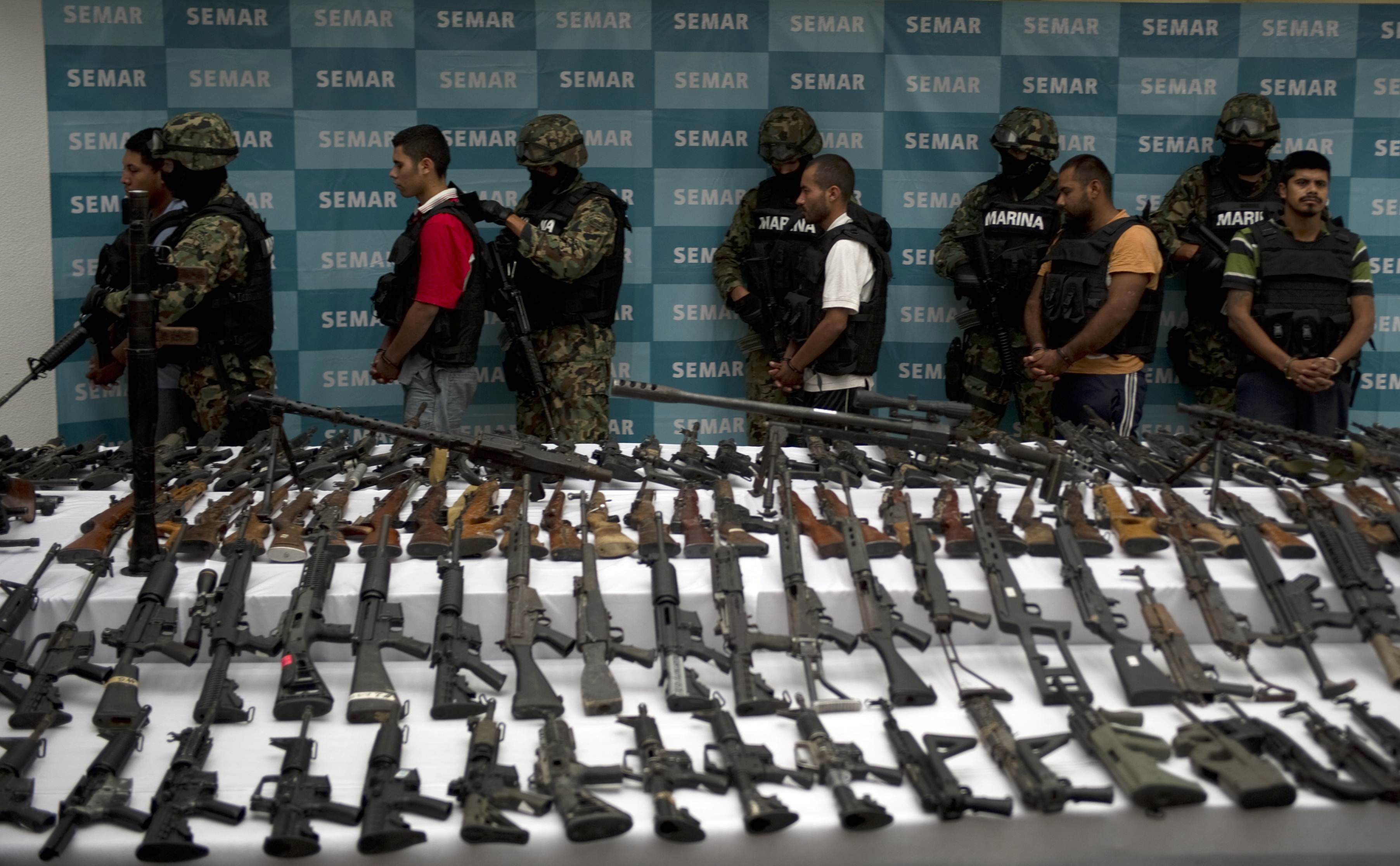 Mexican marines escort five alleged drug traffickers of the Zetas drug cartel in front seized grenades, firearms, cocaine and military uniforms in Mexico City on June 9, 2011. (Yuri Cortez/AFP/Getty Images)