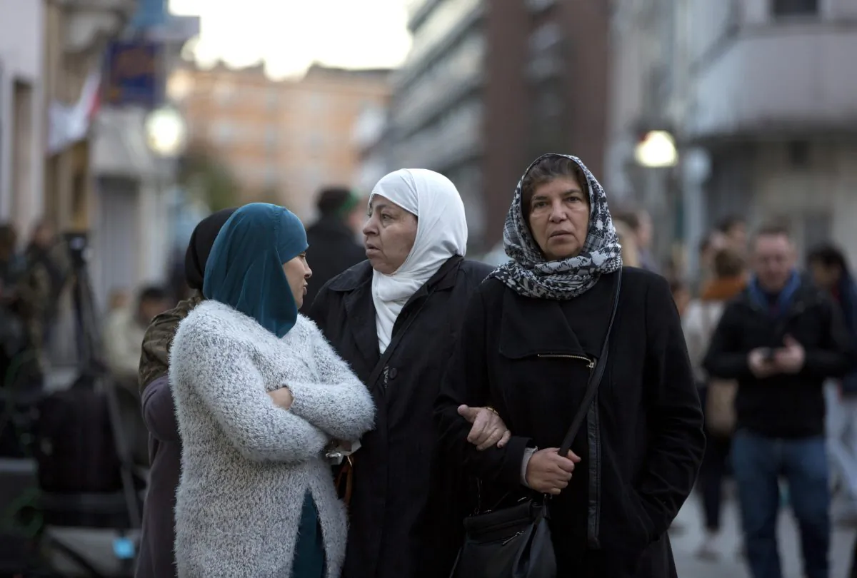 People walk during a candlelight vigil in the town square of Molenbeek, Belgium, on Nov. 18, 2015. Molenbeek was home to a core of the participants in the Paris attacks; its reported architect Abdelhamid Abaaoud and brothers Brahim and Salah Abdeslam. Moreover, those involved in at least two previous attacks, the foiled shooting on a French train and an attack on the Jewish Museum in Brussels all had links to Molenbeek. (AP Photo/Virginia Mayo)