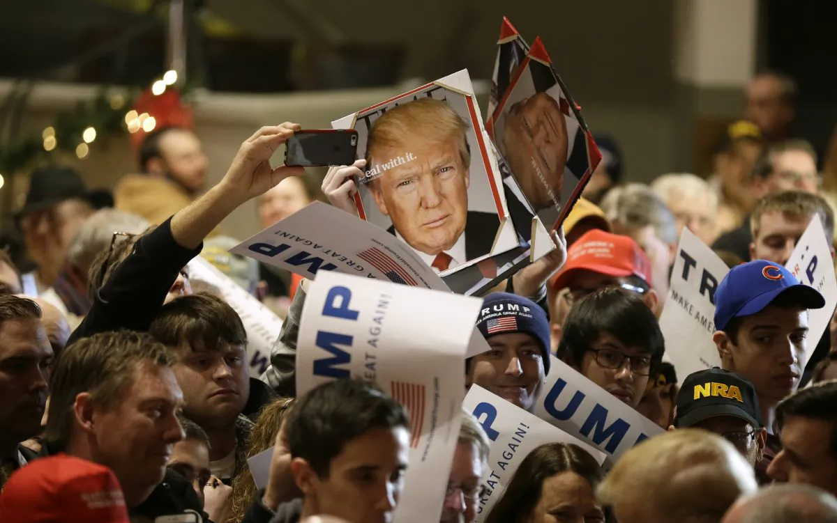 Audience members hold signs to be autographed by Republican presidential candidate Donald Trump during a campaign rally at the Veterans Memorial Building, Saturday, Dec. 19, 2015, in Cedar Rapids, Iowa. (AP Photo/Charlie Neibergall)