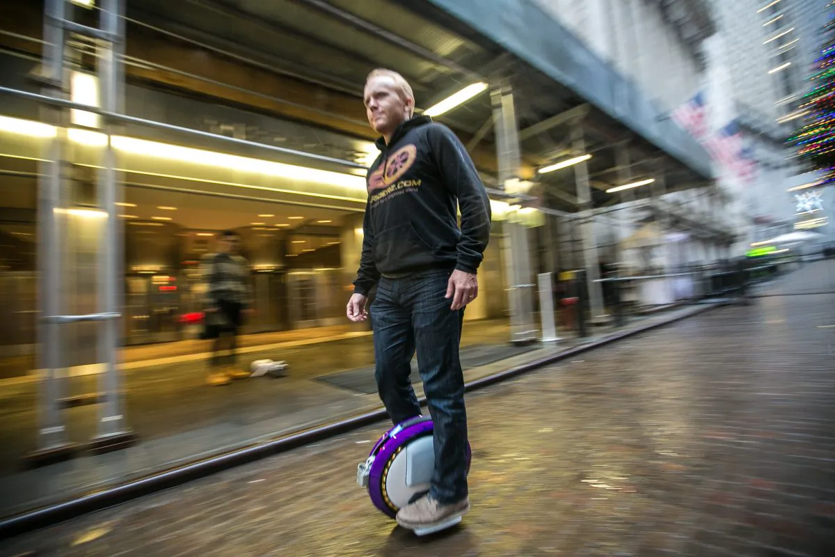 Tim Haden, founder of Hoodriderz, rides a Ninebot One electric wheel next to the New York Stock Exchange building in Manhattan on Dec. 18, 2015. (Benjamin Chasteen/Epoch Times)
