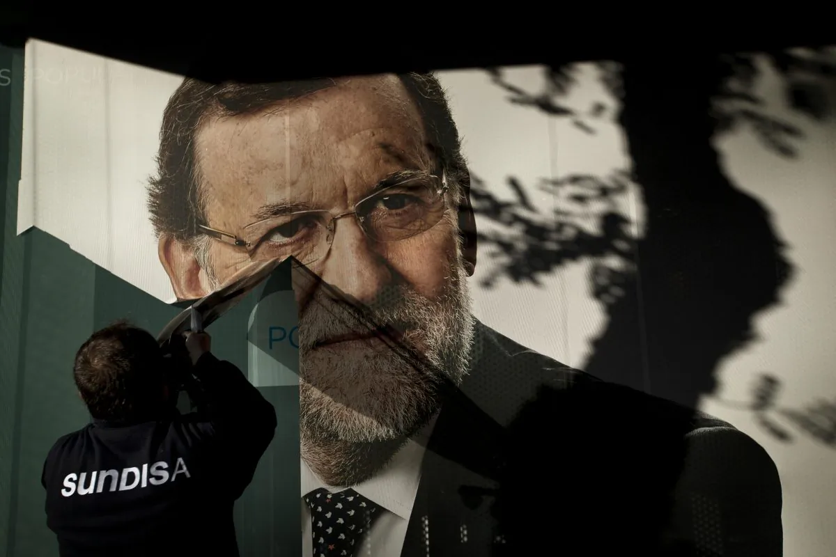 A worker removes a campaign poster for the national elections depicting Spain's acting Prime Minister and Popular Party candidate Mariano Rajoy, in Madrid, Monday, Dec. 21, 2015. Spanish political parties Monday faced what are likely to be tough negotiations to form a government after the country rejected the dominating two-party scene of recent decades and elected a fragmented Parliament. The ruling conservative Popular party came first with 123 seats in Sunday's election but fell far short of a 176 majority needed to govern alone and way below the 186 seats it won in 2011. (AP Photo/Emilio Morenatti)