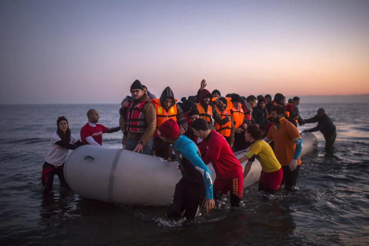 Volunteers help refugees and migrants who are approaching the Greek island of Lesbos on a dinghy after crossing the Aegean sea from the Turkey's coast on Dec. 7, 2015. (AP Photo/Santi Palacios)