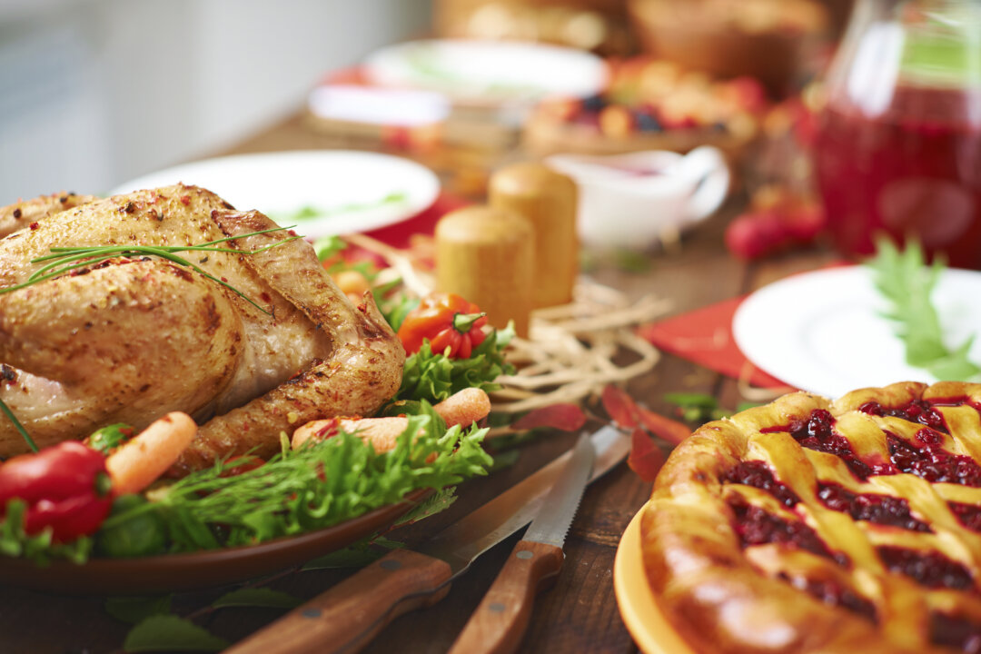 Roasted meat with garnish and cowberry pie on festive table. (shironosov/iStock)