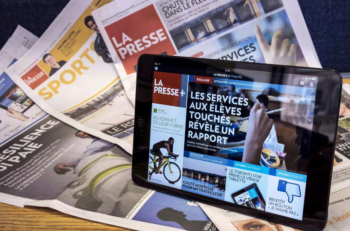 A tablet is seen on the newspaper edition of a La Presse newspaper. Advertisers are packing up their campaigns and moving out of print media at a pace that shows no sign of slowing over the next four years, according to a new report. (The Canadian Press/Paul Chiasson)