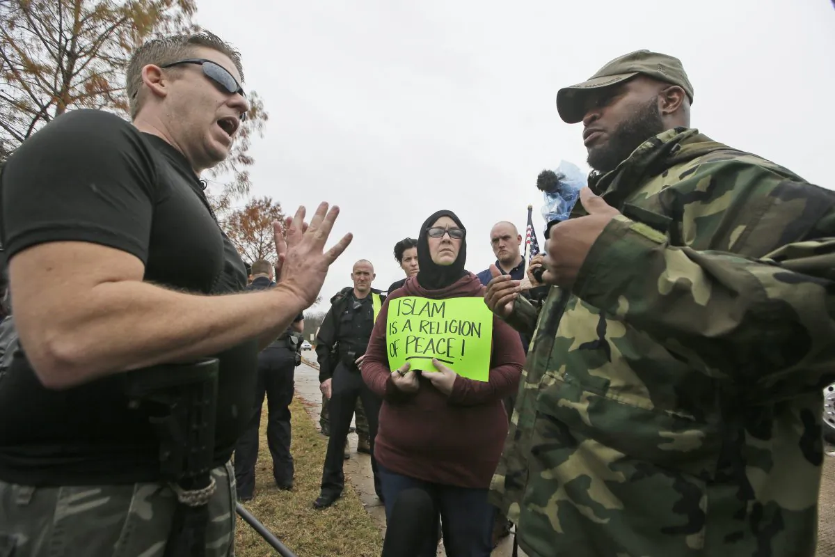 Protester David Wright (L) speaks with counterprotester Vincent Simon, a Muslim, as Melissa Yassini holds a sign across the street from a mosque in Richardson, Texas, on Dec. 12, 2015. (LM Otero/AP Photo)