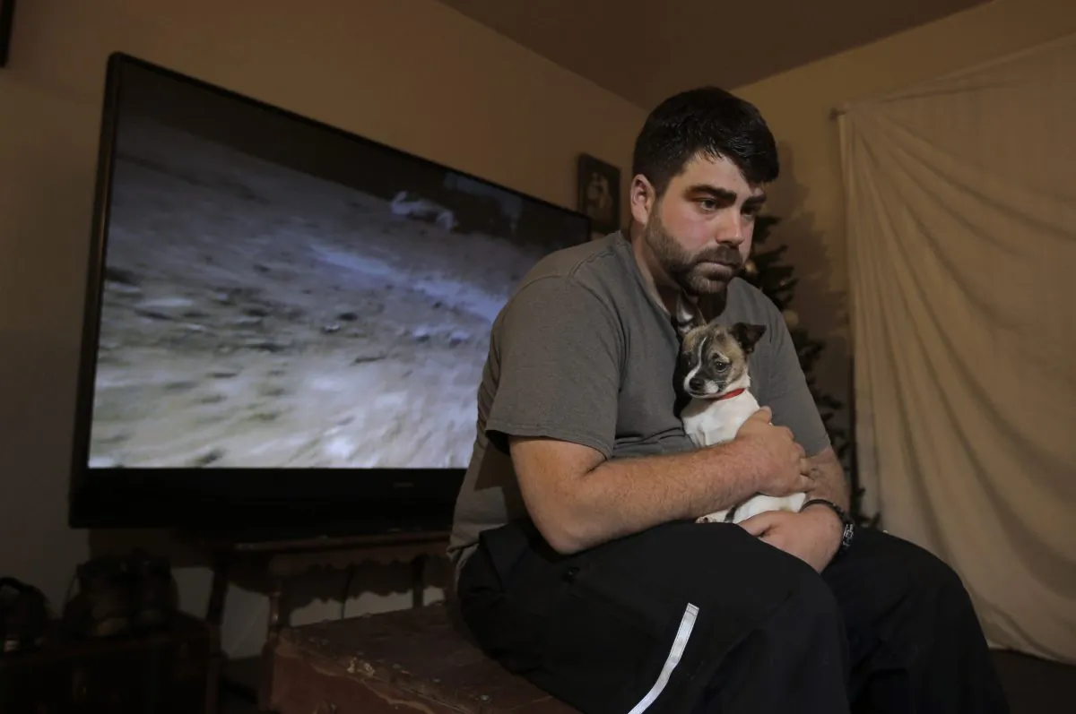 In this photo taken Thursday, Dec. 17, 2015, Josh Redmyer, a former Marine who served three tours in Iraq, poses with Milo, who he calls his "therapy dog," in Oroville, Calif.  Redmyer, who was diagnosed with Post-Traumatic Stress Disorder in 2009,  received a less-than-honorable discharge in 2012. He is among the thousands of veterans who cannot receive veterans health benefits because of a less-than-honorable discharge. Redmyer turns to Milo, who is a birthday present from his roommate, when he becomes despondent. (AP Photo/Rich Pedroncelli)