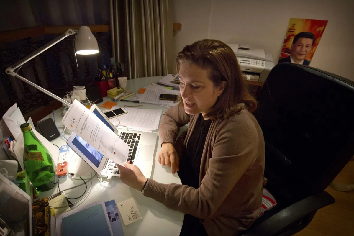 French journalist Ursula Gauthier, a reporter for the French news magazine L'Obs, holds a statement criticizing her from the Chinese Ministry of Foreign Affairs as she sits at her desk in her apartment in Beijing, Saturday, Dec. 26, 2015. (AP Photo/Mark Schiefelbein)