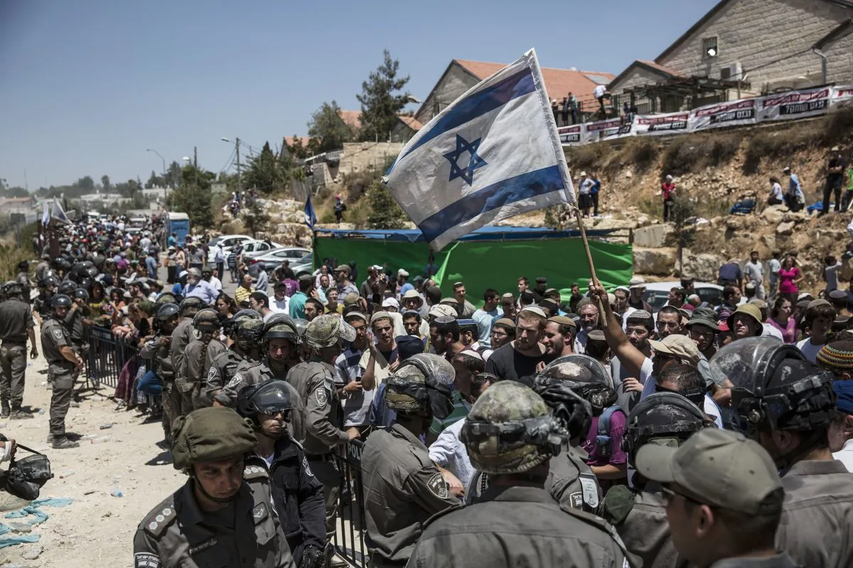Israeli settlers watch the demolition of a building at the Jewish settlement of Beit El, near the West Bank town of Ramallah, on July 29, 2015. Israeli bulldozers began demolishing a contested housing complex in a West Bank settlement as the prime minister’s office announced the “immediate construction” of some 300 new units at another location in the same settlement and advanced plans for about 500 new units in east Jerusalem. (AP Photo/Tsafrir Abayov)