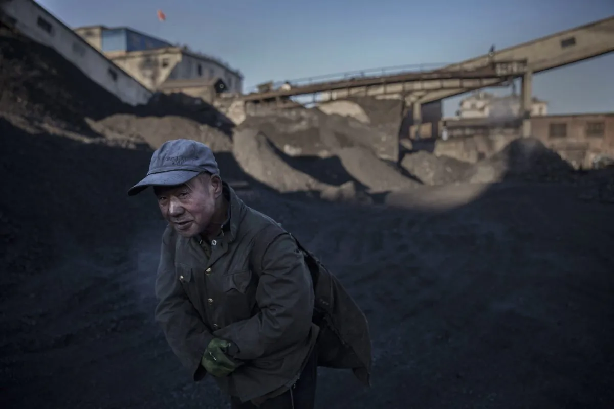 A Chinese man carries coal he collected from a sorting area at a coal mine on November 25, 2015 in Shanxi, China. (Kevin Frayer/Getty Images)