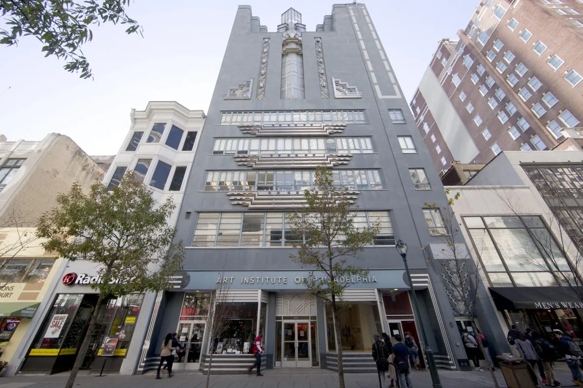 People walk past the Art Institute of Philadelphia operated by the Education Management Corporation in Philadelphia on Nov. 16, 2015. The Obama administration has reached a $95.5 million settlement with a Pittsburgh firm that runs for-profit trade schools and colleges. The Justice Department settlement resolves allegations that Education Management Corporation used enrollment incentives to pay its recruiters and exaggerated its career-placement ability. (AP Photo/Matt Rourke)