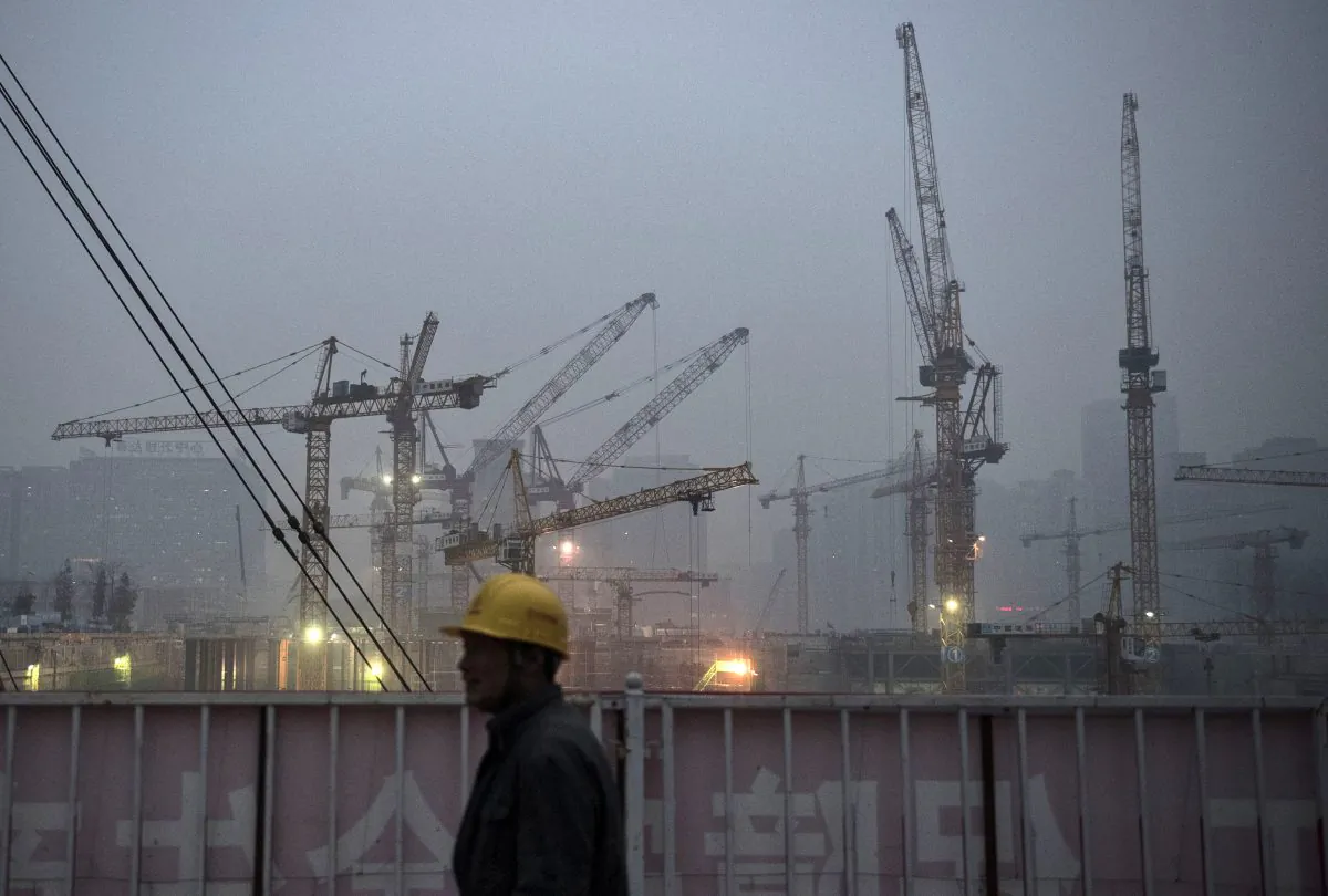 A Chinese laborer is backdropped by cranes at a construction site on December 9, 2014 in Beijing, China. (Kevin Frayer/Getty Images)