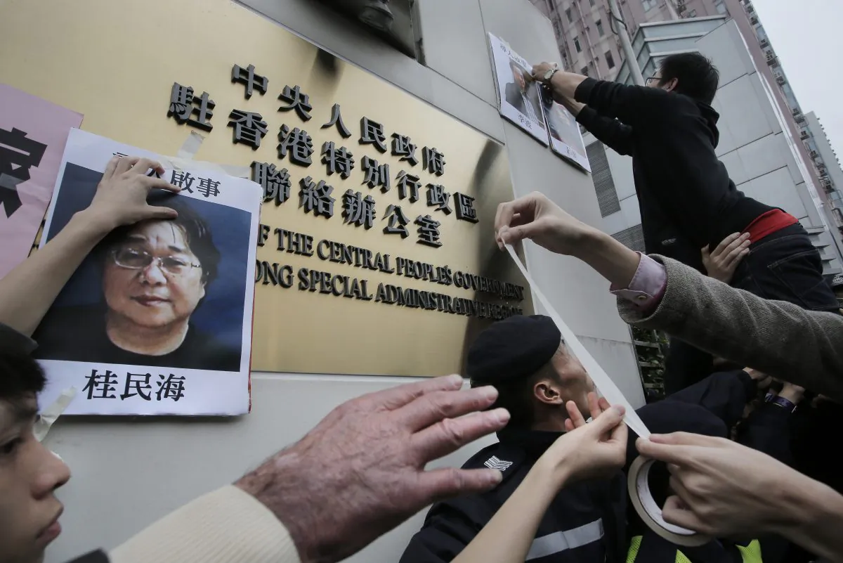 Protesters try to stick photos of missing booksellers during a protest outside the Liaison of the Central People's Government in Hong Kong on Jan. 3, 2016. (AP Photo/Vincent Yu)
