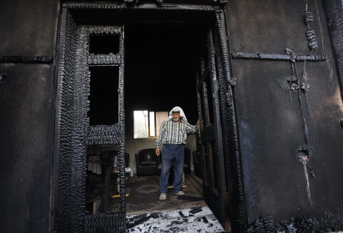 A Palestinian inspects a house on July 31, 2015, after it was torched in a suspected attack by Jewish settlers, killing an 18-month-old Palestinian child and his parents, at Duma village near the West Bank city of Nablus. Israel on Sunday indicted two Jewish extremists suspected in the attack, a case that has been unsolved for months and helped fuel the current wave of Israeli-Palestinian violence. (AP Photo/Majdi Mohammed)